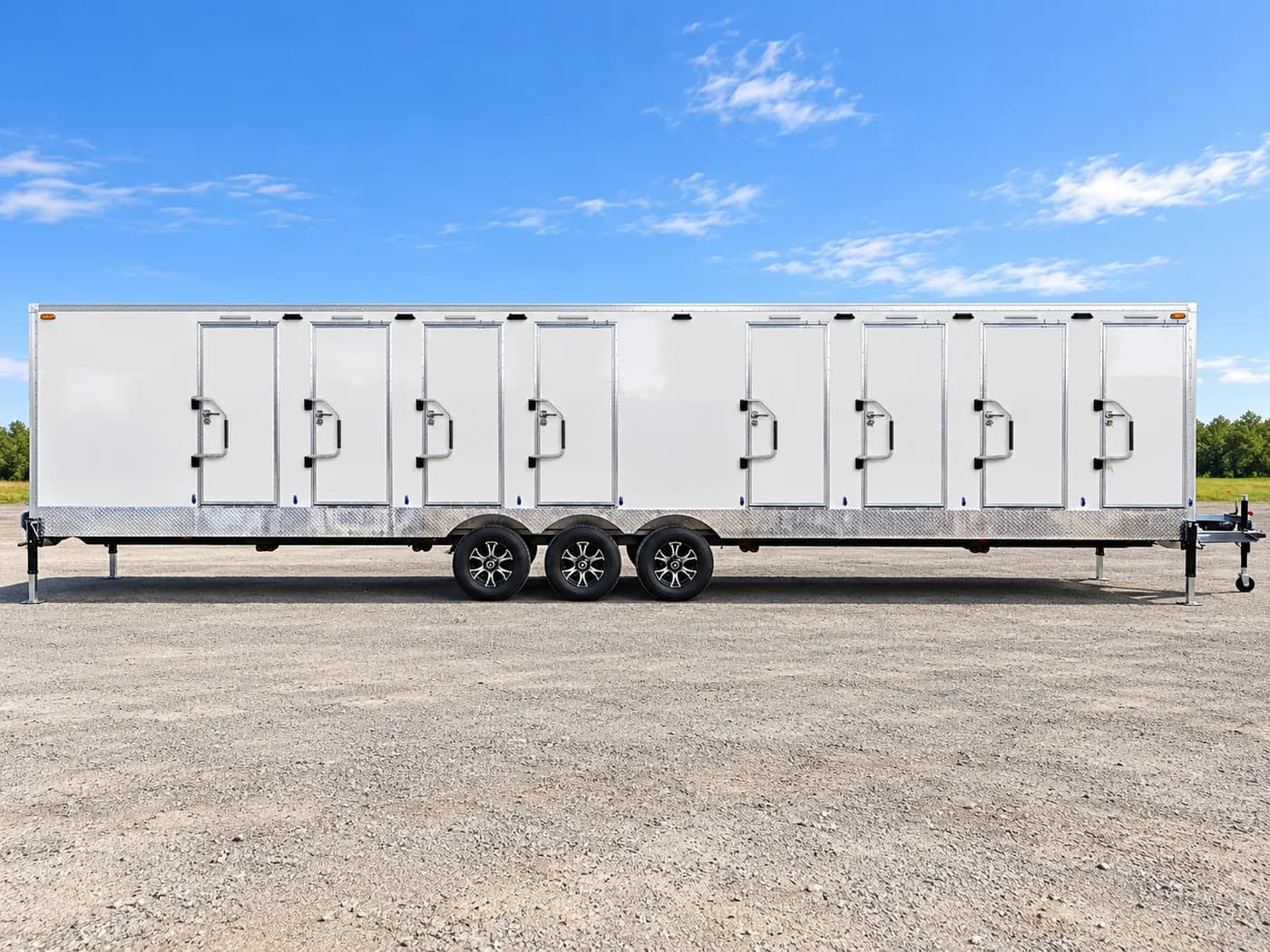Side view of a triple-axle shower and restroom combination trailer with a row of stall doors